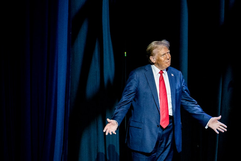 Donald Trump holds his arms out as he walks on stage at the Detroit Economic Club