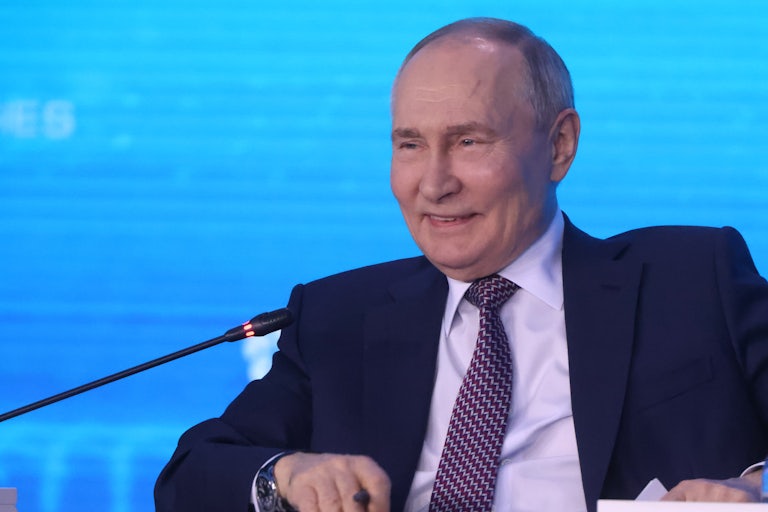 Russian President Vladimir Putin laughs while on a panel.