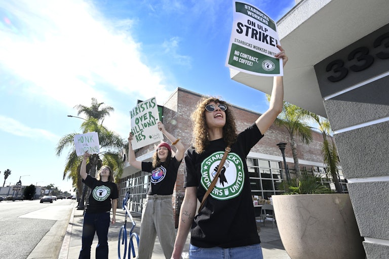 Starbucks workers protest with signs that read "Baristas over billionaires," "Honk for Unions," and "Starbucks Workers on ULP Strike."