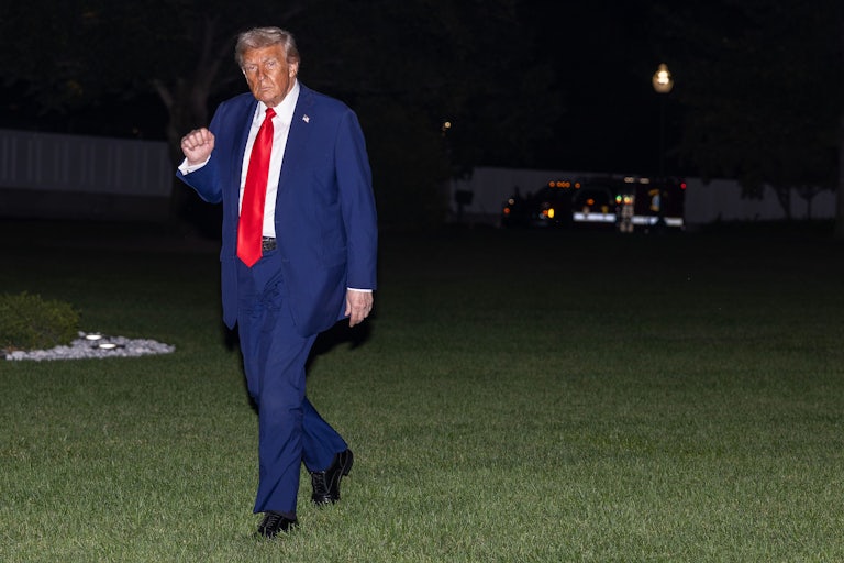Donald Trump raises his fist while walking outside the White House