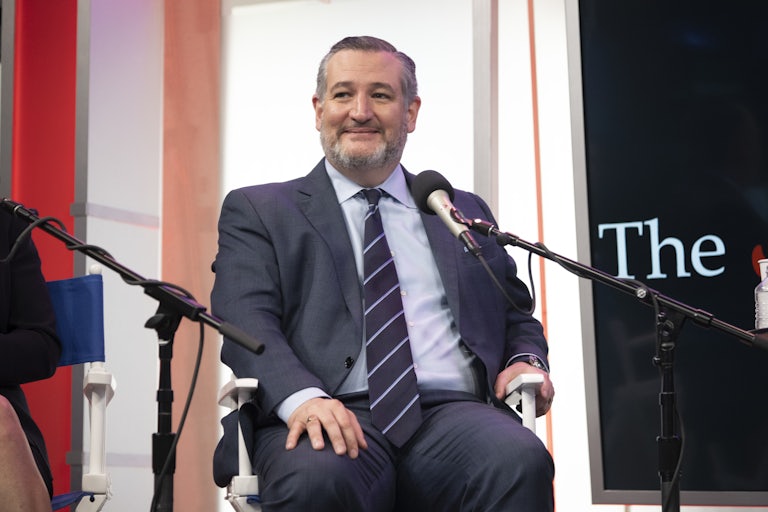 Ted Cruz smiles as he sits in front of a microphone