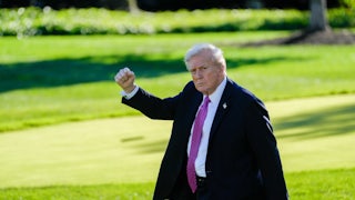 Donald Trump raises his fist while walking outside the White House