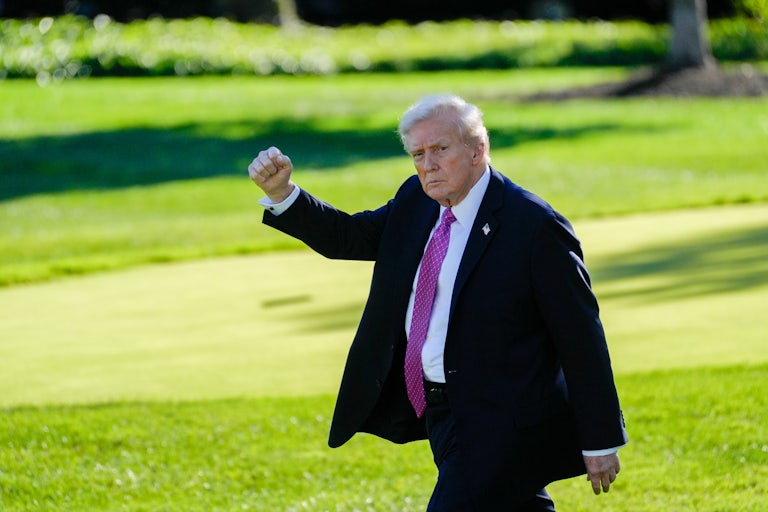 Donald Trump raises his fist while walking outside the White House