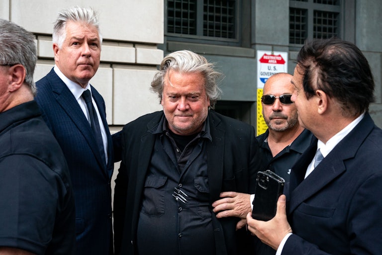 Steve Bannon and attorney Matthew Evan Corcoran depart the courthouse. Other men surround them.