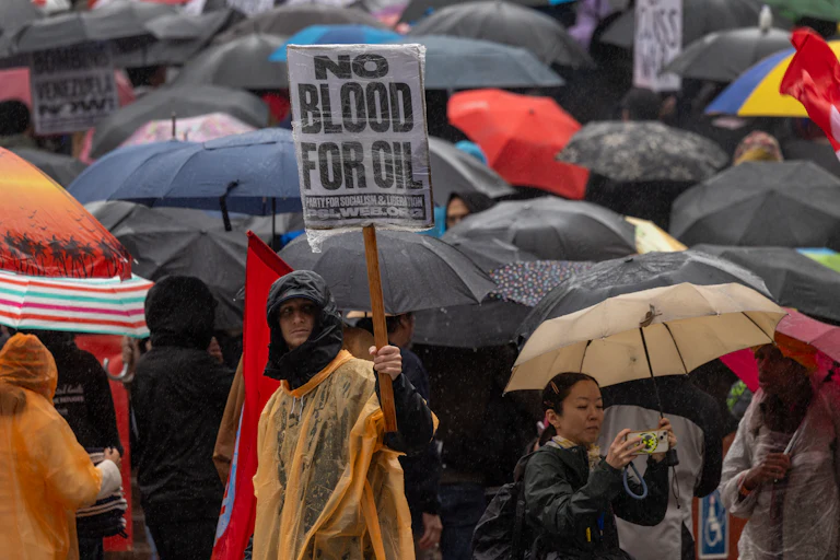 a protester holds up a sign reading "no blood for oil"