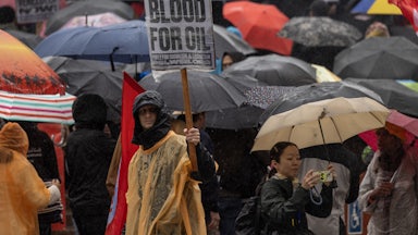 a protester holds up a sign reading "no blood for oil"