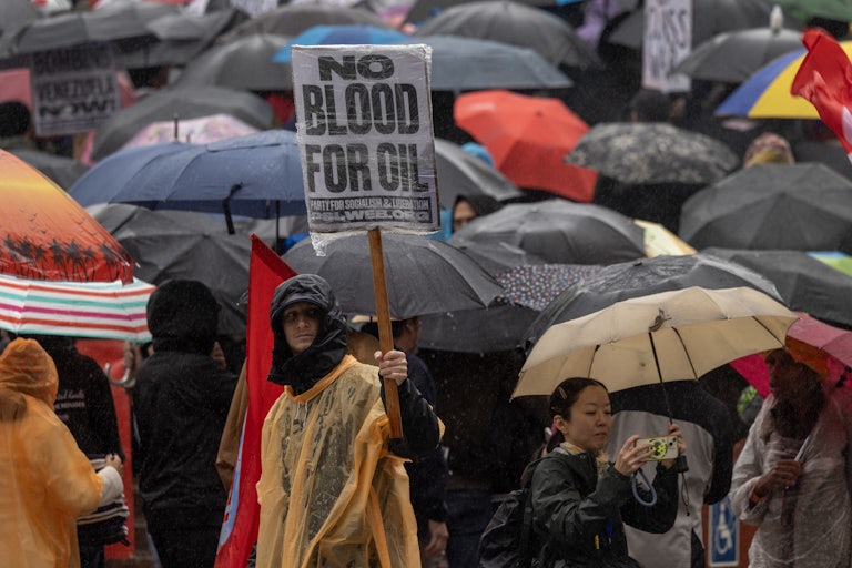 a protester holds up a sign reading "no blood for oil"