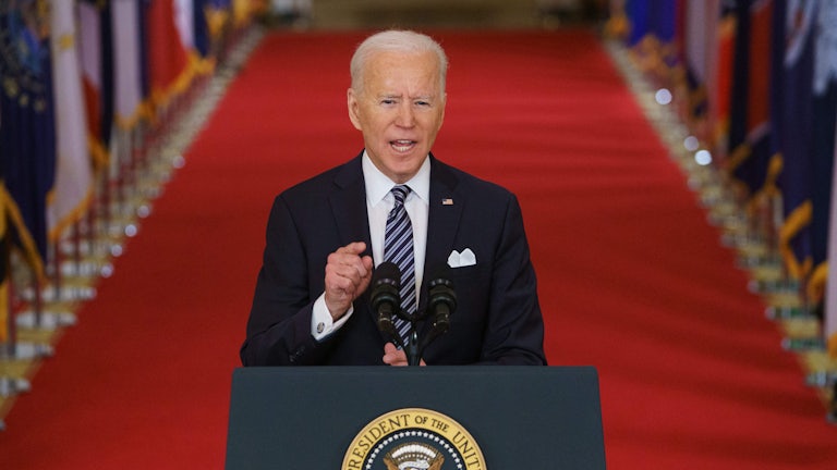 Joe Biden at a microphone, giving a speech about the coronavirus pandemic in the East Room of the White House