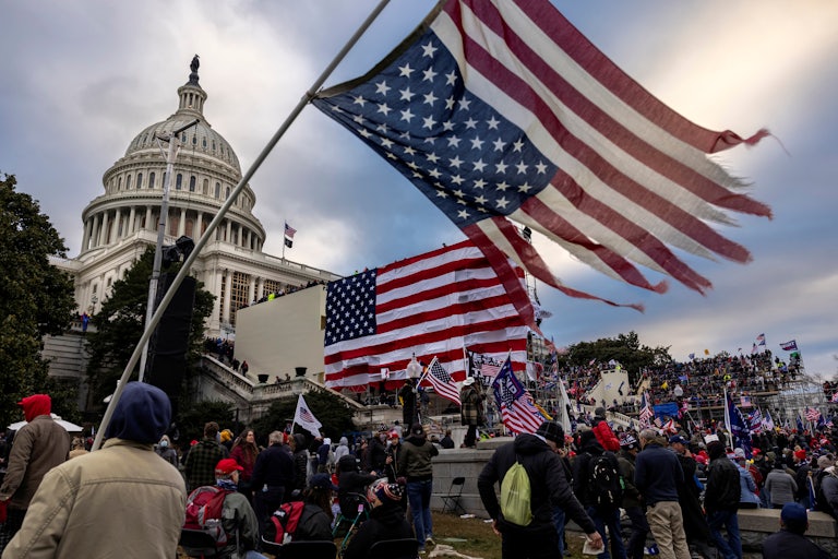 Pro-Trump rioters gather in front of the Capitol on January 6, 2021. A shredded U.S. flag is in the foreground.