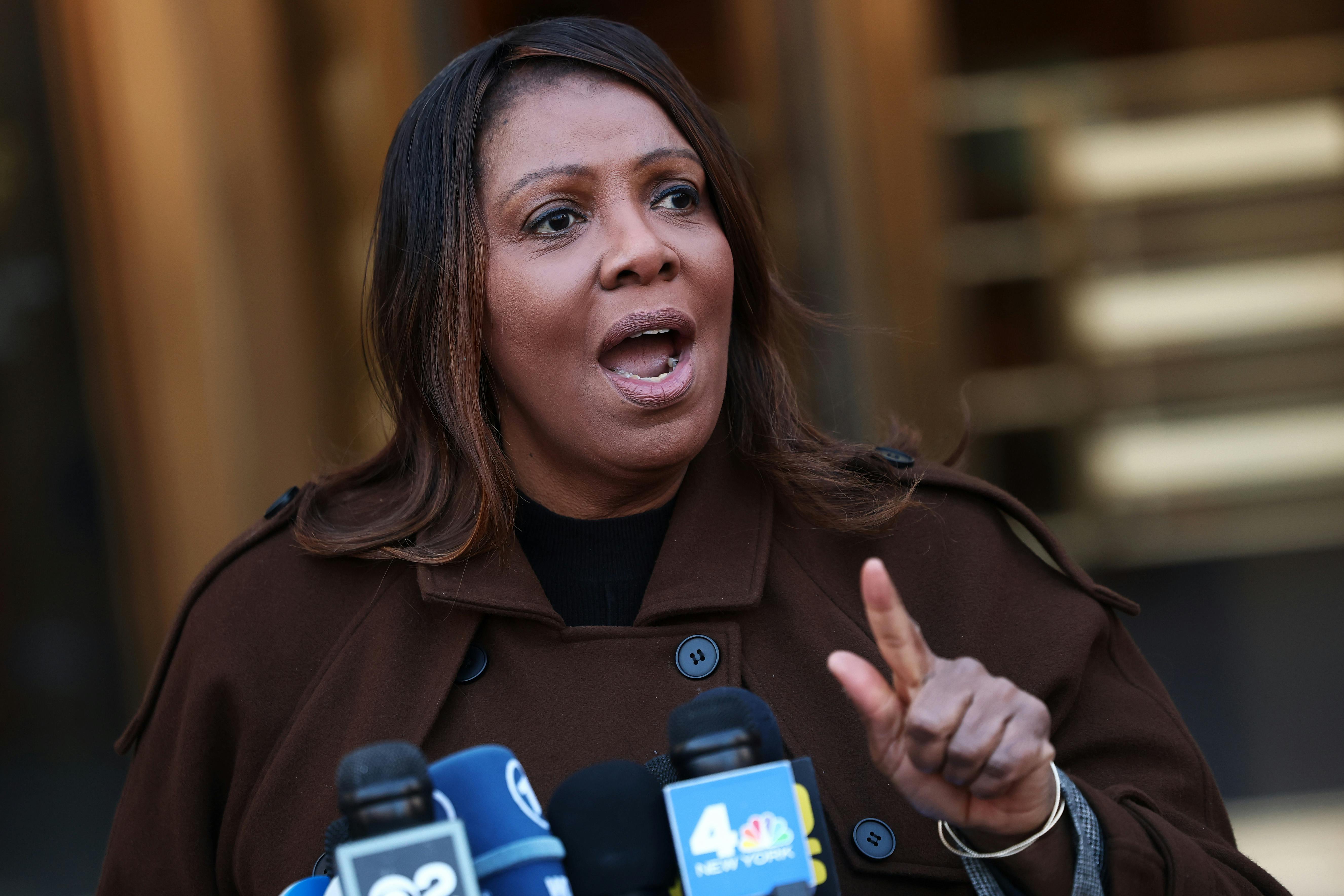 New York Attorney General Letitia James speaks at a lectern with reporters' microphones.