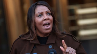 New York Attorney General Letitia James speaks at a lectern with reporters' microphones.