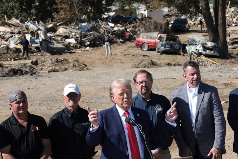 Donald Trump speaks in front of rubble from Hurricane Helene. He is flanked by several Republican allies.