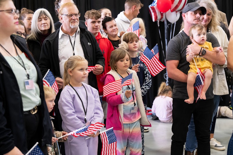 White Afrikaners stand and wave small American flags after arriving at Dulles Airport from South Africa