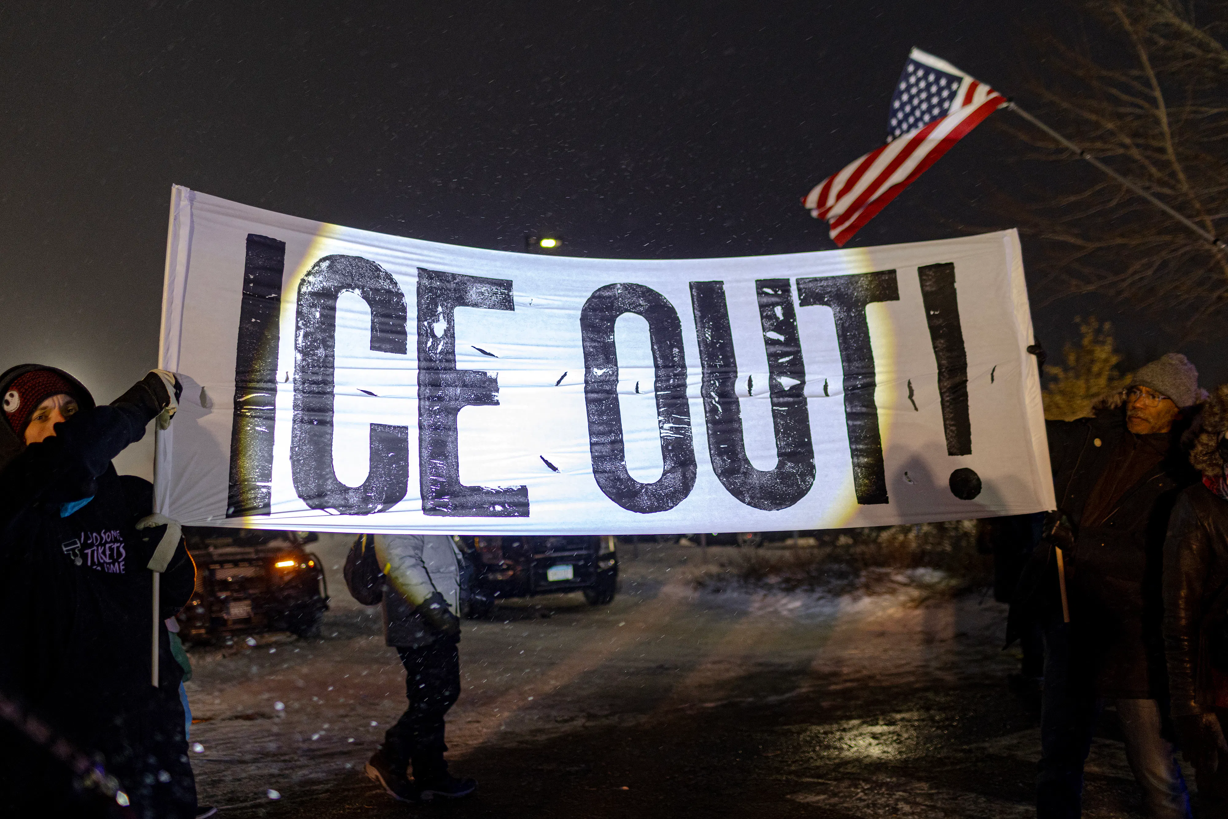 People hold up a banner that says, "ICE out!" during a protest in Minneapolis, Minnesota