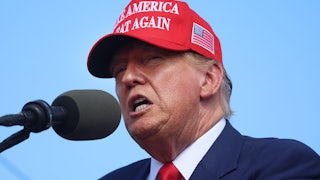 Donald Trump wearing a MAGA cap and speaking into a microphone