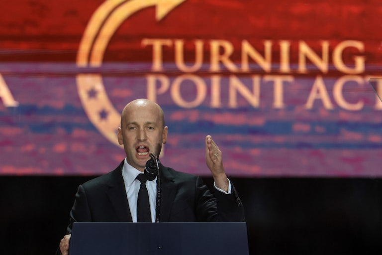 Stephen Miller gives a speech at Charlie Kirk's memorial in front of a large screen that says Turning Point Action.