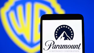 The Paramount Skydance Corporation logo is seen on a smartphone with the Warner Bros. logo in the background.