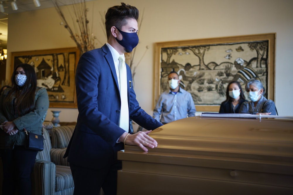 The manager of Perches Funeral Home pushes the casket of Humberto Rosales, a care provider who died of Covid-19 complications.