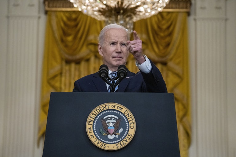 President Joe Biden stands pointing behind a lectern.
