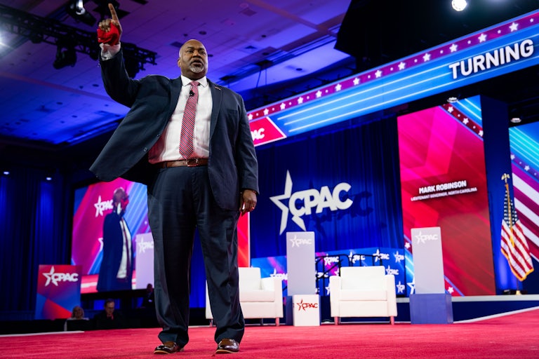Mark Robinson stands with his right hand raised on a stage