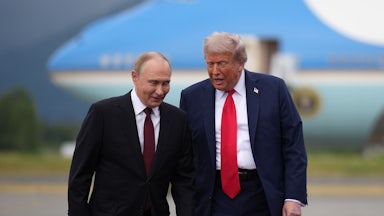 U.S. President Donald Trump walks with Russian President Vladimir Putin on a red carpet, as a plane is in the backgorund.