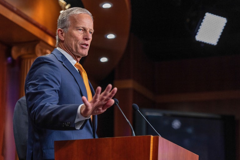 Senate Majority Leader John Thune gestures while speaking at a podium