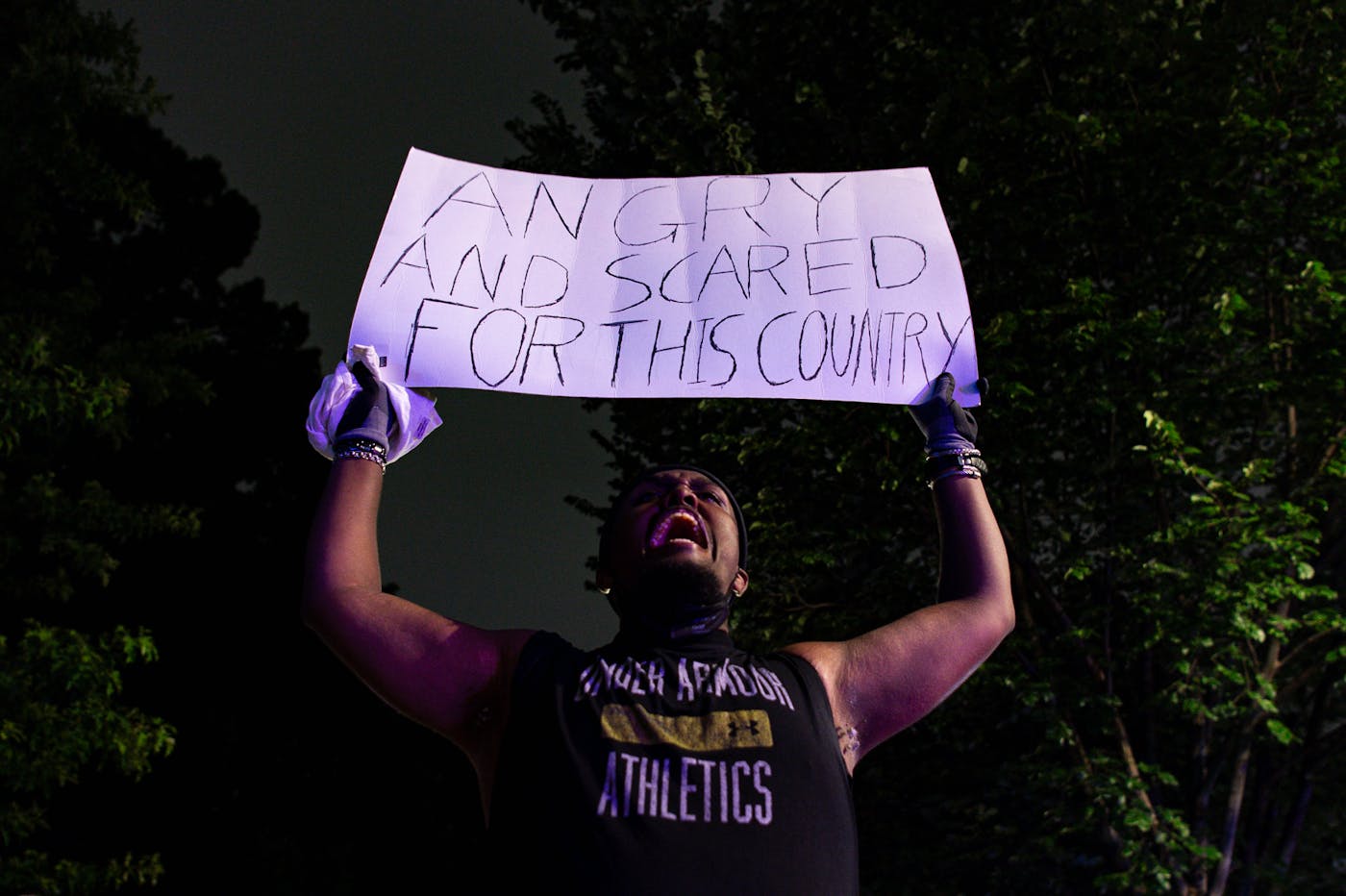 A demonstrator holds a sign reading, “Angry and scared for this country,” during a protest at the Army’s 250th birthday celebration and Trump’s 79th birthday rally,
