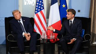 U.S. President Donald Trump sways to the side as French President Emmanuel Macron speaks with him.