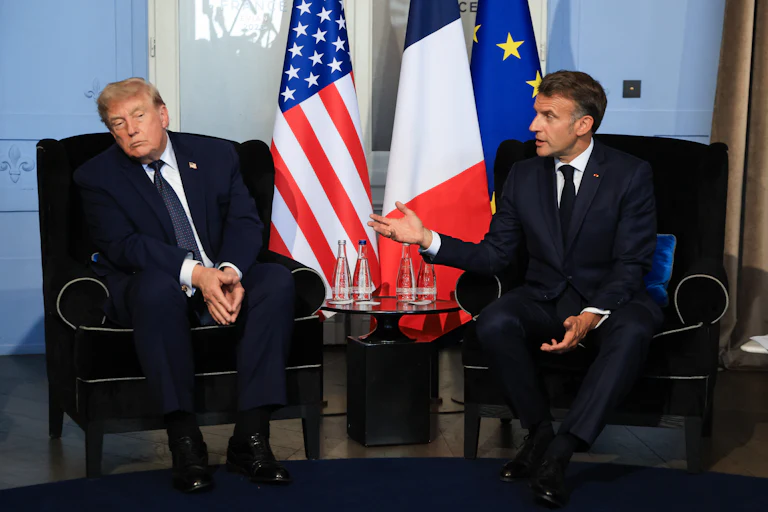 U.S. President Donald Trump sways to the side as French President Emmanuel Macron speaks with him.