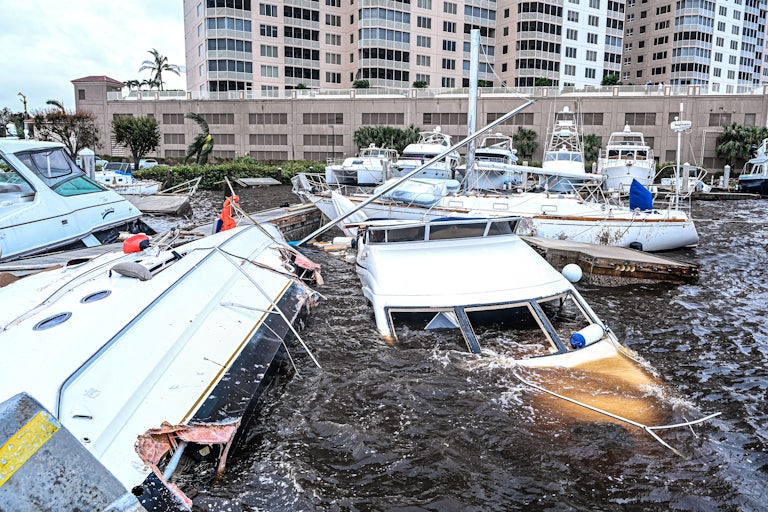 Damaged boats float partially submerged at a marina.