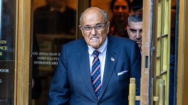Rudy Giuliani frowns while walking out of a courthouse