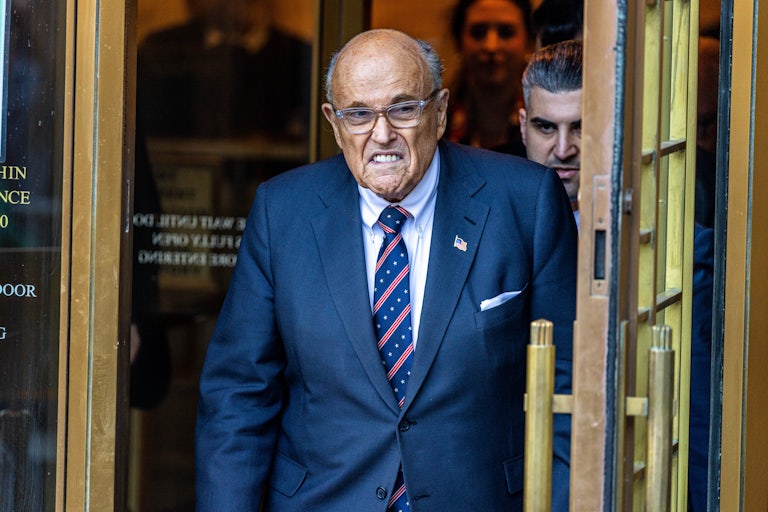 Rudy Giuliani frowns while walking out of a courthouse