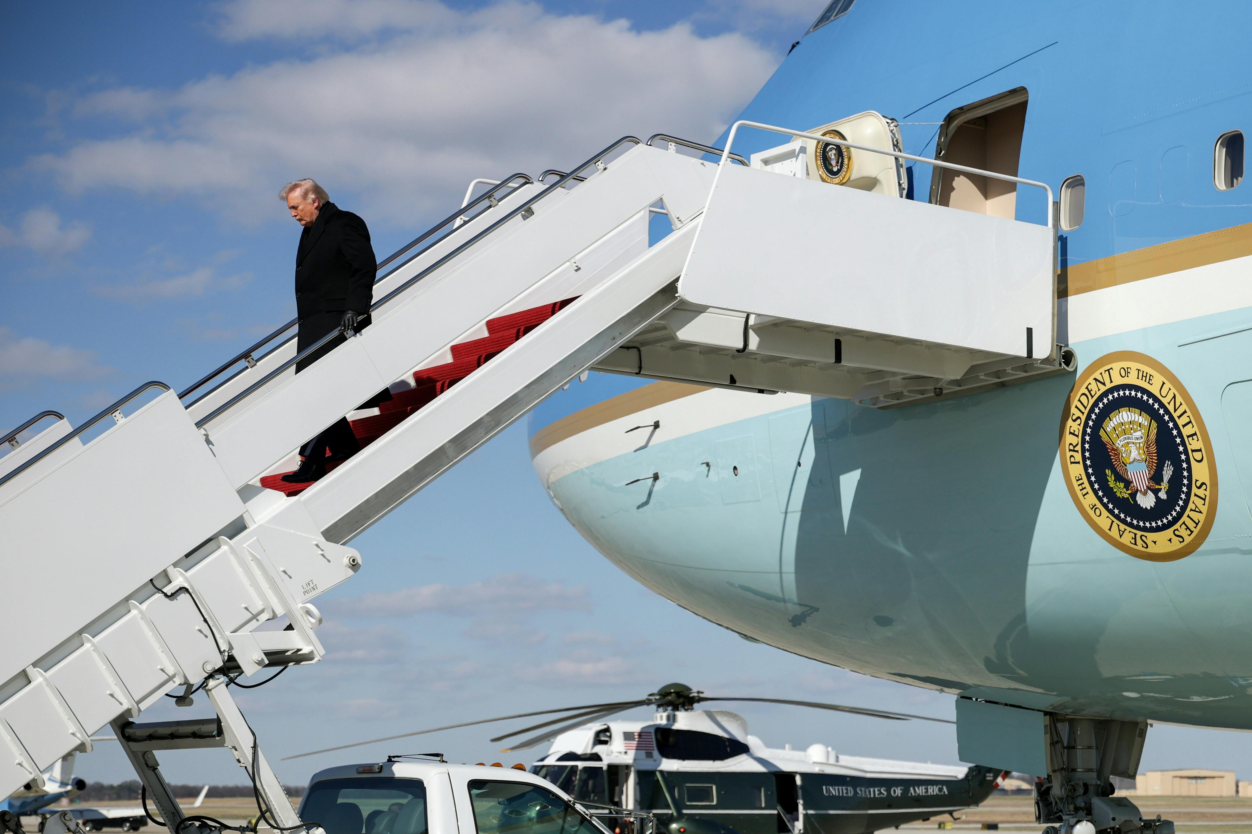 Donald Trump looks down while walking down the stairs from Air Force One