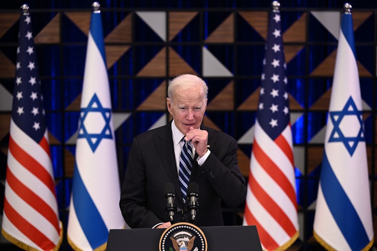 President Joe Biden speaks at a lecturn. Israeli and U.S. flags are behind him.