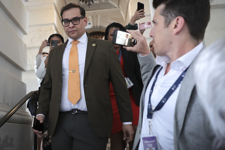 New York Representative George Santos walks down the stairs as reporters surround him