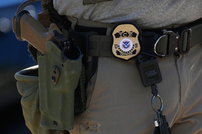 an ICE agent's badge and gun hanging off his belt