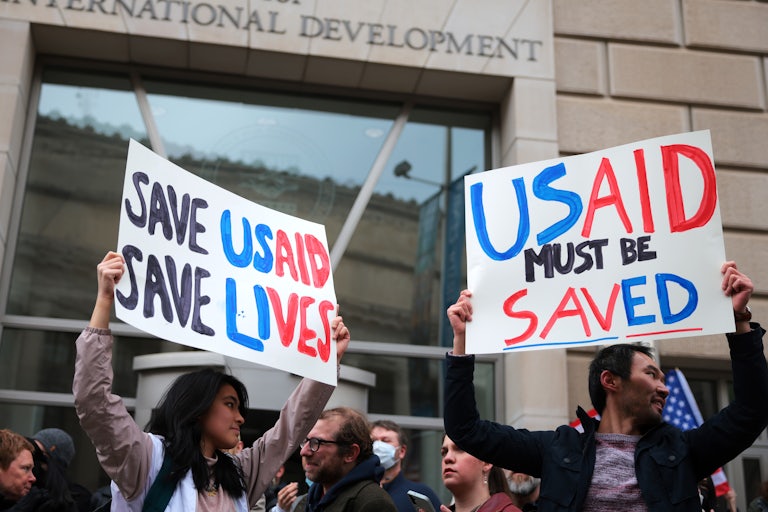 Protesters outside USAID headquarters hold signs that read "Save USAID Save Lives" and "USAID Must Be Saved."