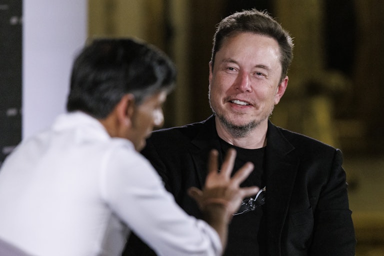 Elon Musk smiles at Rishi Sunak who gesticulates in the foreground.
