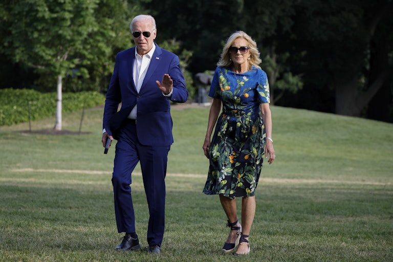 Joe and Jill Biden walk on the lawn. Biden waves to the camera.