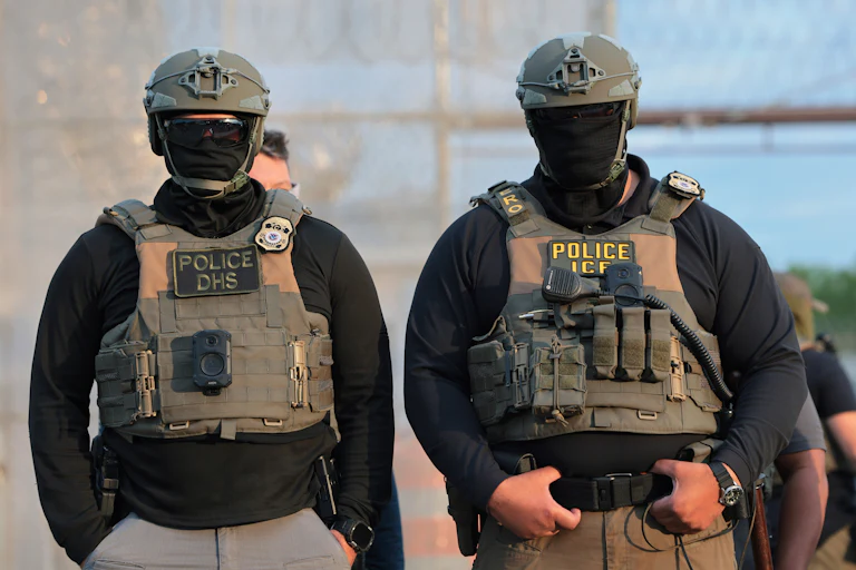 Two masked ICE agents stand outside Delaney Hall in New Jersey