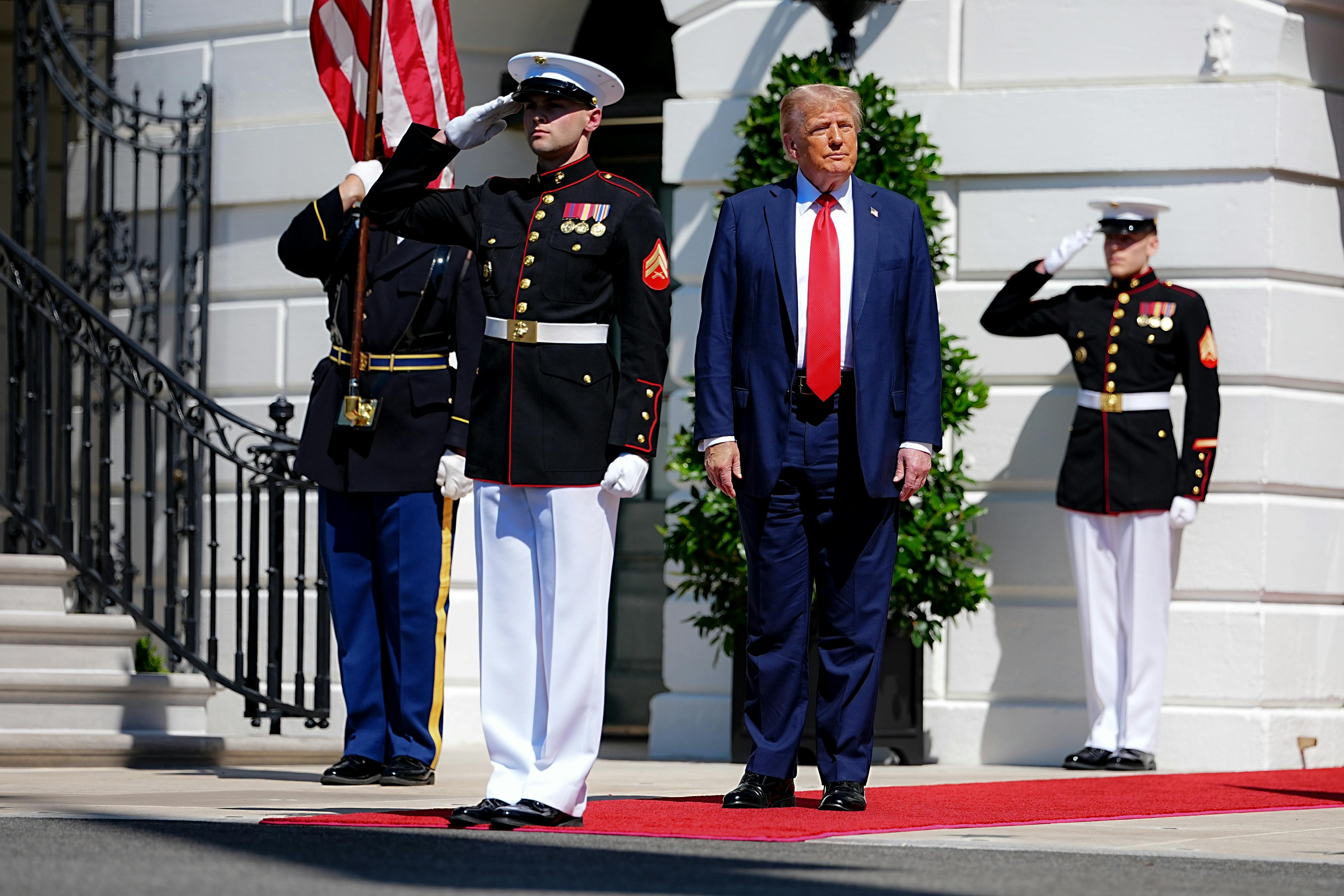 Trump is saluted by Polish soldiers as he stands on a red carpet