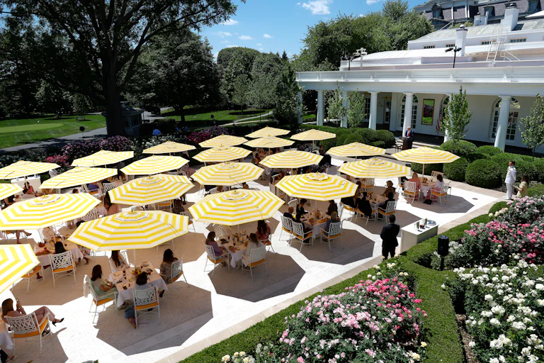 Ugly yellow and white striped umbrellas above tables on the Rose Garden patio