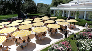 Ugly yellow and white striped umbrellas above tables on the Rose Garden patio