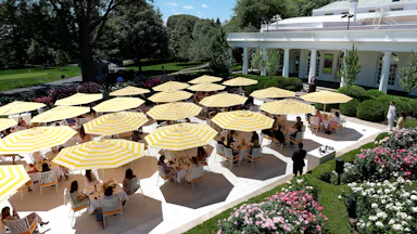 Ugly yellow and white striped umbrellas above tables on the Rose Garden patio