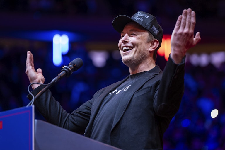 Elon Musk holds his arms out while speaking at a Donald Trump rally