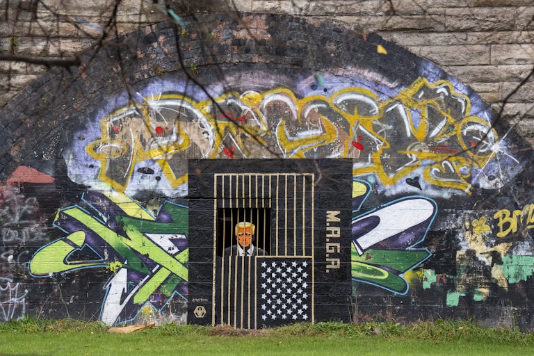 A piece of street art, by artist Ashley Rawson, depicting President Donald Trump behind bars