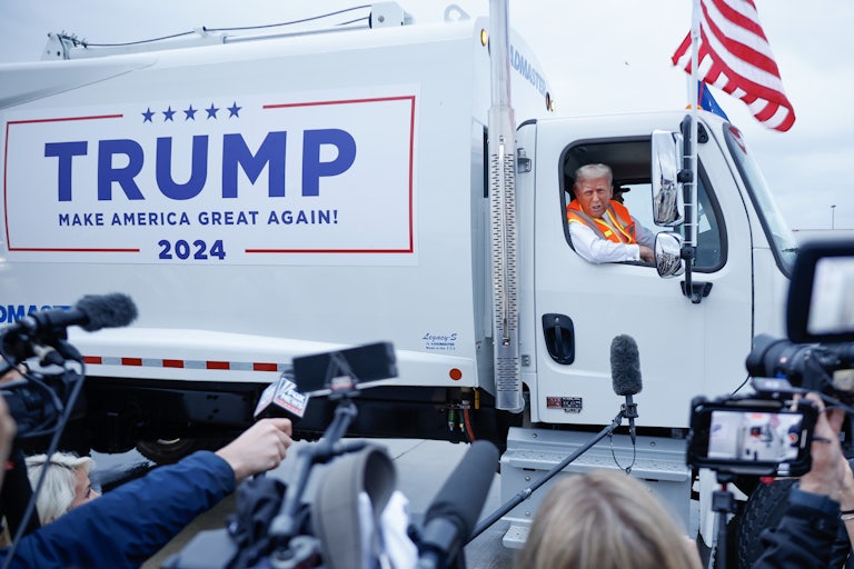 Donald Trump speaks to reporters while sitting in a campaign-branded garbage truck