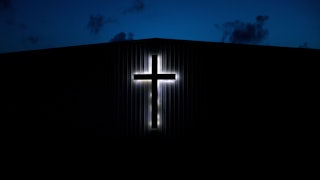 An illuminated cross on a church