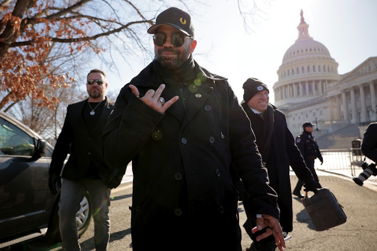 Former Proud Boys leader Enrique Tarrio leaves the Capitol, holding up his fingers in a gesture similar to "Rock and Roll."