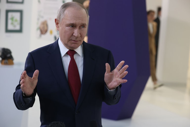 Russian President Vladimir Putin speaks with his hands as he talks to reporters.